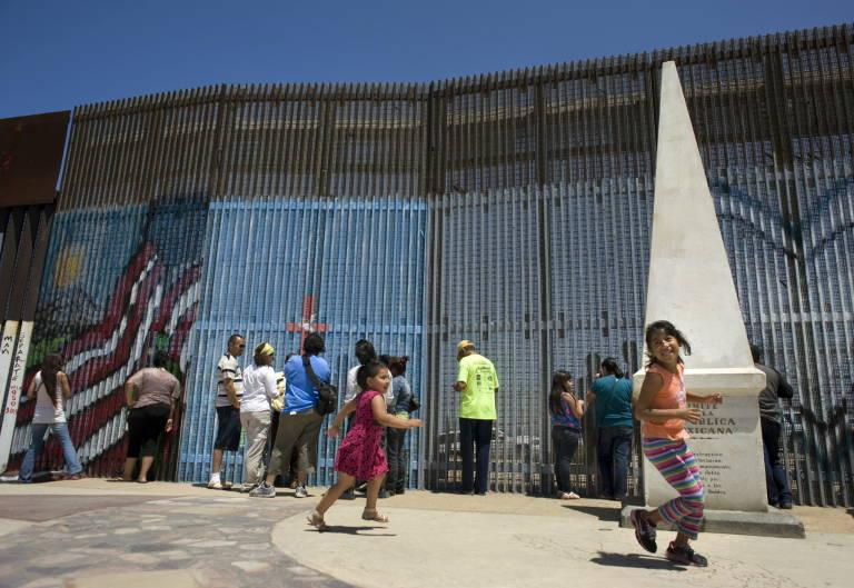 Familias se reúnen junto a una valla metálica en el Parque de la Amistad en Tijuana, que separa EEUU de México. Foto: EFE/DAVID MAUNG